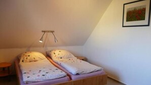 A small, single-bed room with a sloped ceiling and a simple wooden bed frame. - Schwalbenring by Interhome (Rövershagen)