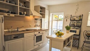 Een moderne keuken met witte kastjes, een roestvrijstalen fornuis en een schaal fruit op het eiland.