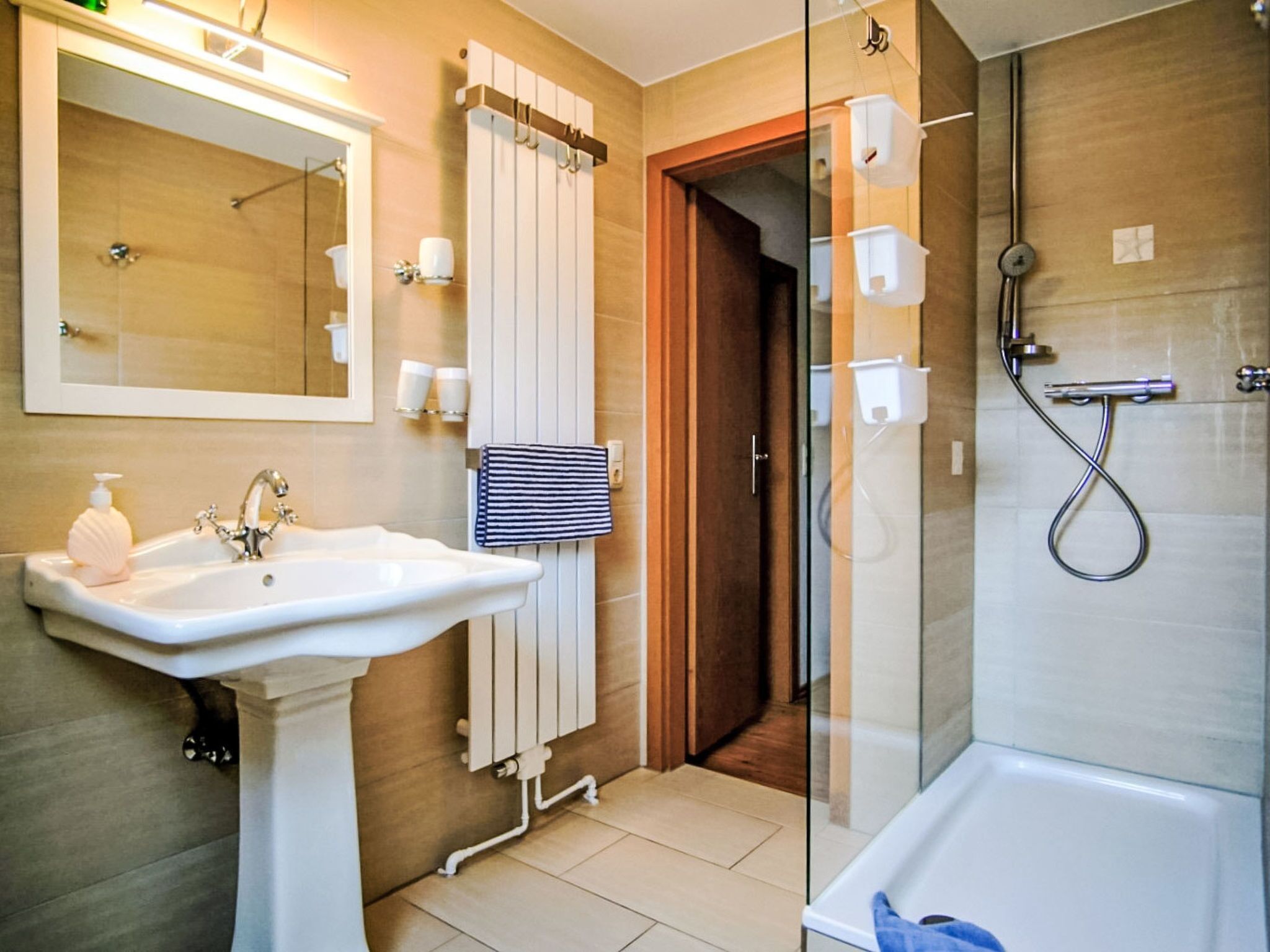 Une salle de bain moderne équipée d’un lavabo, d’un miroir, d’un porte-serviettes, d’une douche et d’une paroi de douche en verre.