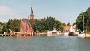 Een haven met boten, een kerk en een bebost heuvel.