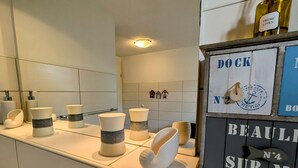 A hotel bathroom with white fixtures, a mirror, and a signboard with the text "DOCK" and "BEAU" visible. - Apartment 55qm by Interhome (Ahrenshoop)