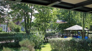 A covered outdoor area with a garden, a gazebo, and a table with chairs. - Apartment 55qm by Interhome (Ahrenshoop)
