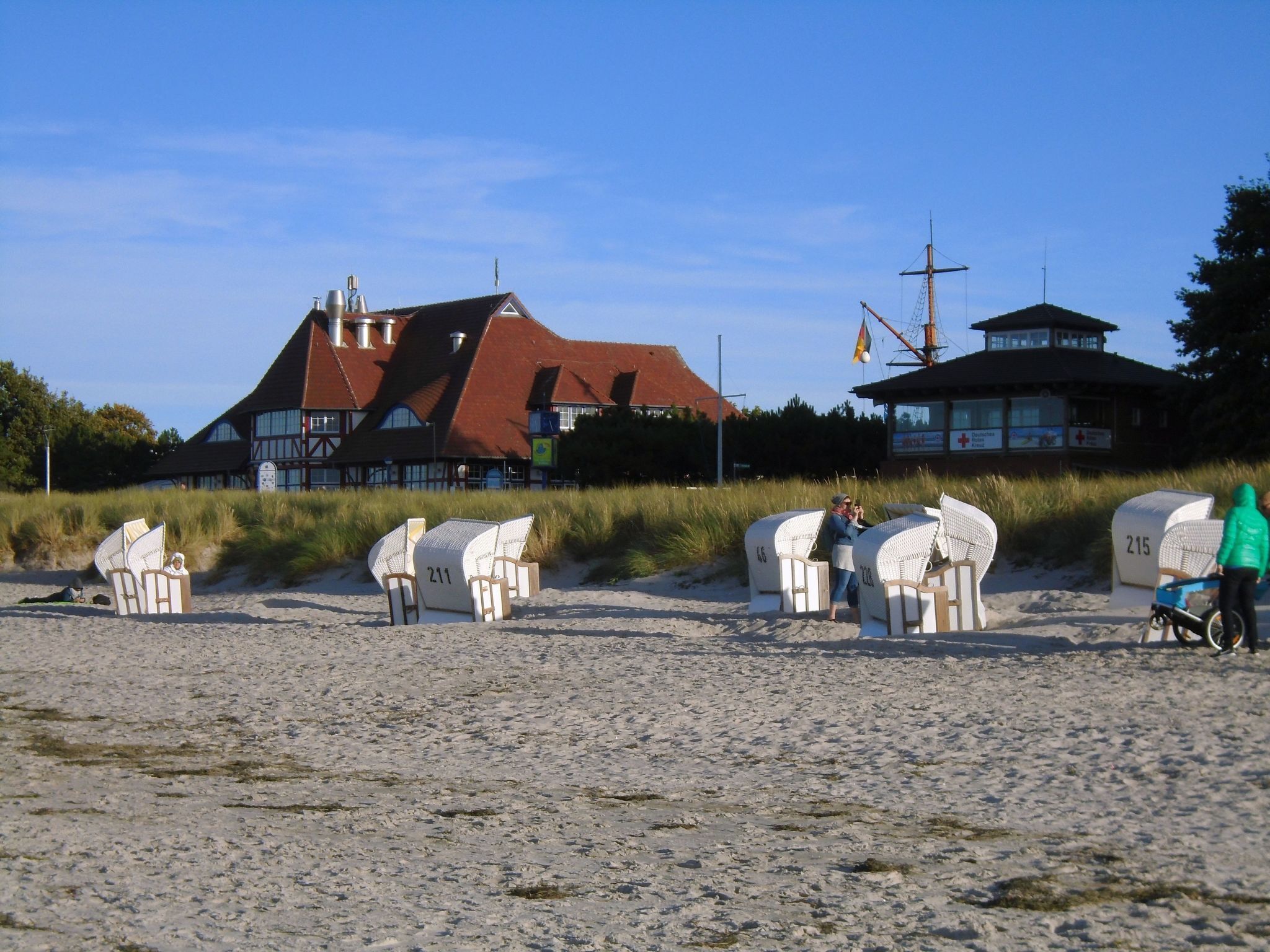 A beach with beach chairs numbered 211, 216, and 215, and a lifeguard tower in the background.