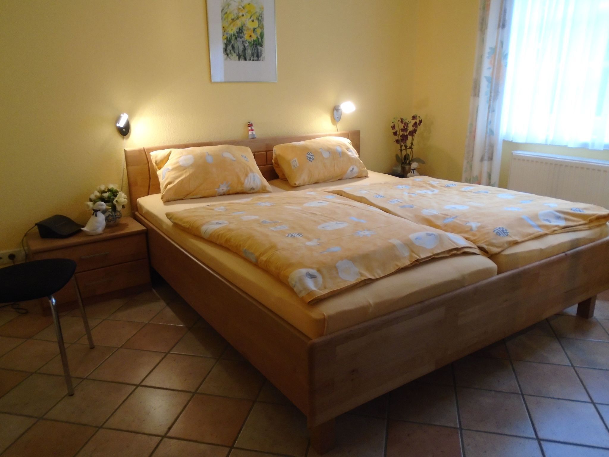 Ein Schlafzimmer mit einem hölzernen Bett, zwei Nachttischen, einem Beistelltisch, einem Stuhl und einer Wandlampe.
