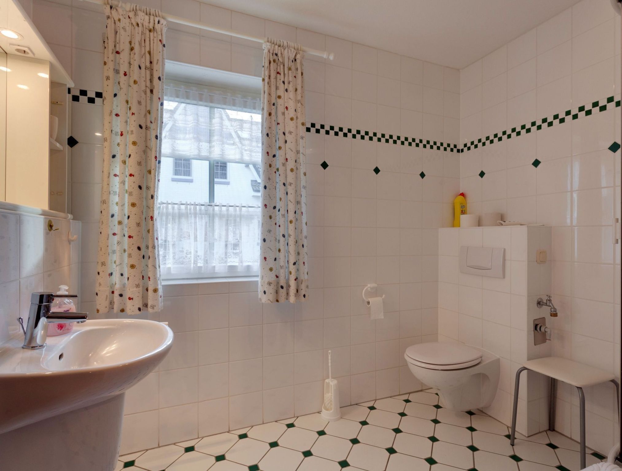 A bathroom with a sink, toilet, and window with curtains.