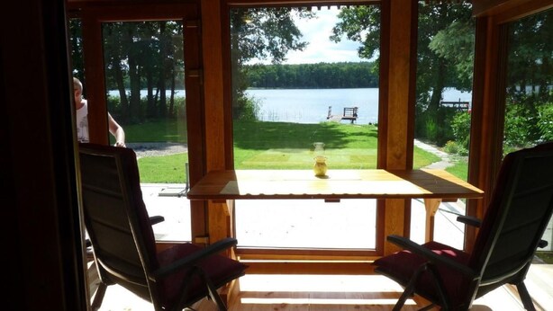 Une cabane en bois avec une table et deux chaises, donnant sur un lac.
