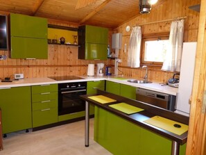 Een koelkast, een oven, een vaatwasser, kookgerei, borden en bestek