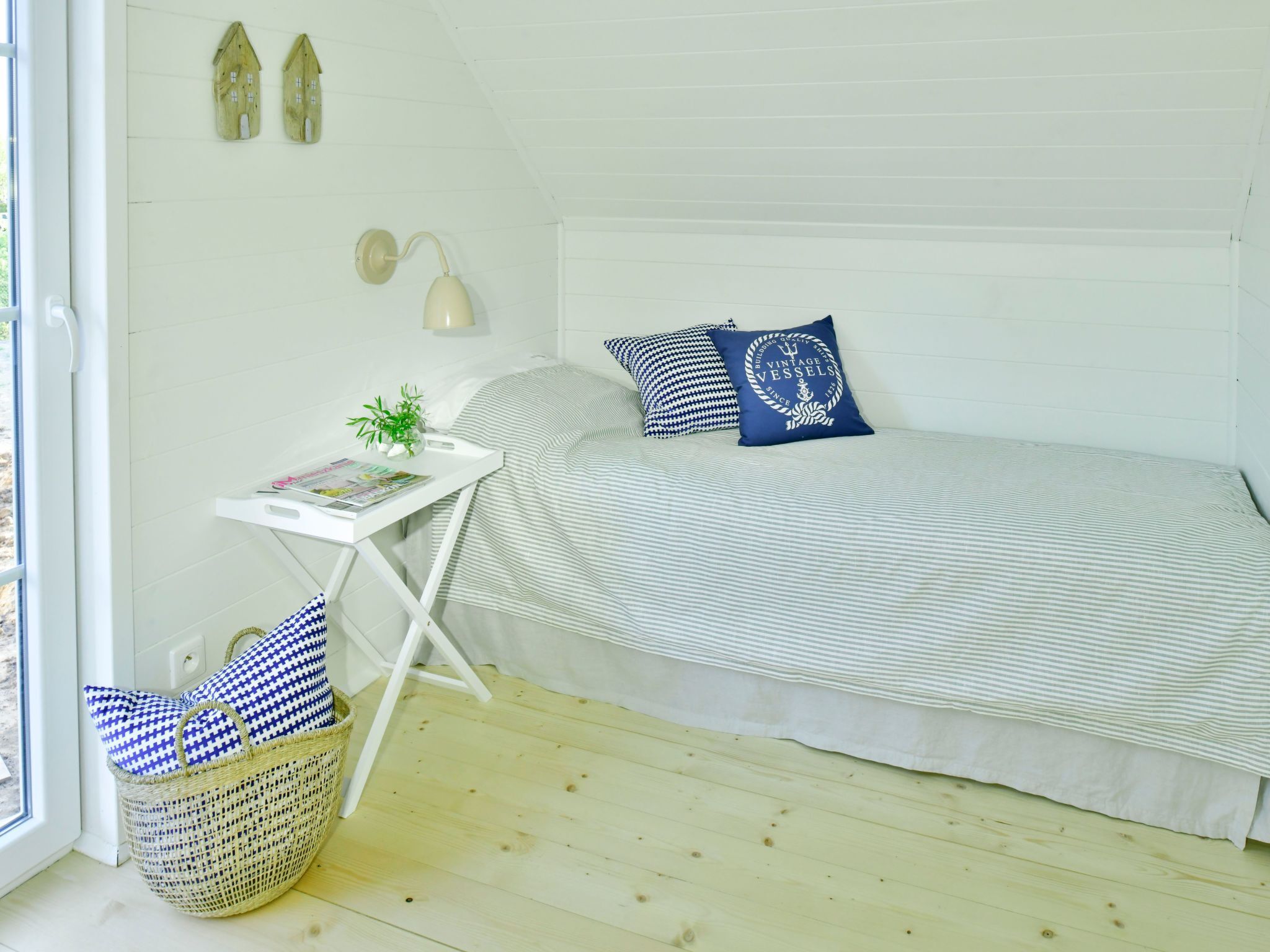 A bedroom with a bed, bedside table, lamp, and a window.