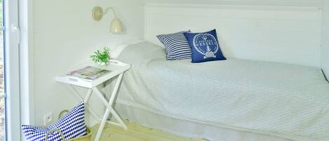 A bedroom with a bed, bedside table, lamp, and a window.