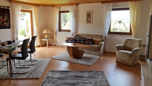 Amplia sala de estar con techo de madera, un sofá, una mesa de centro y un comedor con sillas y una mesa.