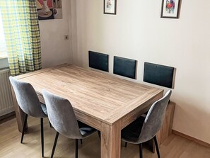 Una mesa de comedor con cuatro sillas, un radiador y una pared con tres cuadros enmarcados.