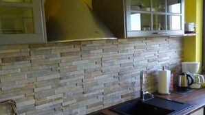 Eine Küche mit Steinrückwand, einem schwarzen Spülbecken und einer Kaffeemaschine auf der Arbeitsplatte.