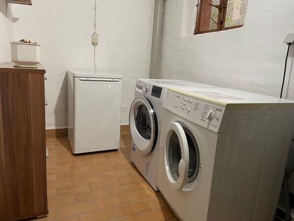A laundry room with a washing machine and dryer, a wooden cabinet, and a tiled floor.