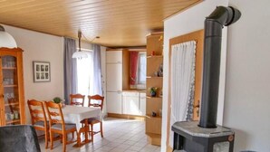 Una habitación acogedora con una mesa de comedor, sillas, estufa y un armario.
