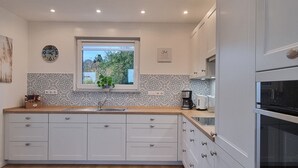 Una cucina moderna con mobili bianchi, una finestra vista, una sveglia e una macchina da caffè.
