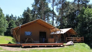 A wooden cabin with a porch, a small deck, and a covered area. - Safarizelt in Hohenlychen mit Garten und Grill by Interhome (Lychen)