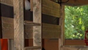 A bunk bed with a wooden ladder, a small table, and a window with a view of greenery. - Safarizelt in Hohenlychen mit Garten und Grill by Interhome (Lychen)