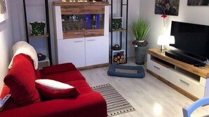 Ein modernes Wohnzimmer mit einem roten Sofa, einem Fernseher und einer Holzkommode mit Glastüren.