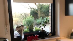 Eine Küche mit Fenster, einem weißen Tisch und einem Stuhl.