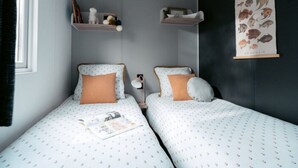 Quarto com duas camas, cada uma com um travesseiro e uma pequena prateleira acima.