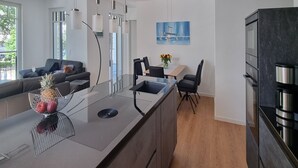 A modern kitchen with a central island, black chairs, and a dining table. - Strandblick by Interhome (Binz)