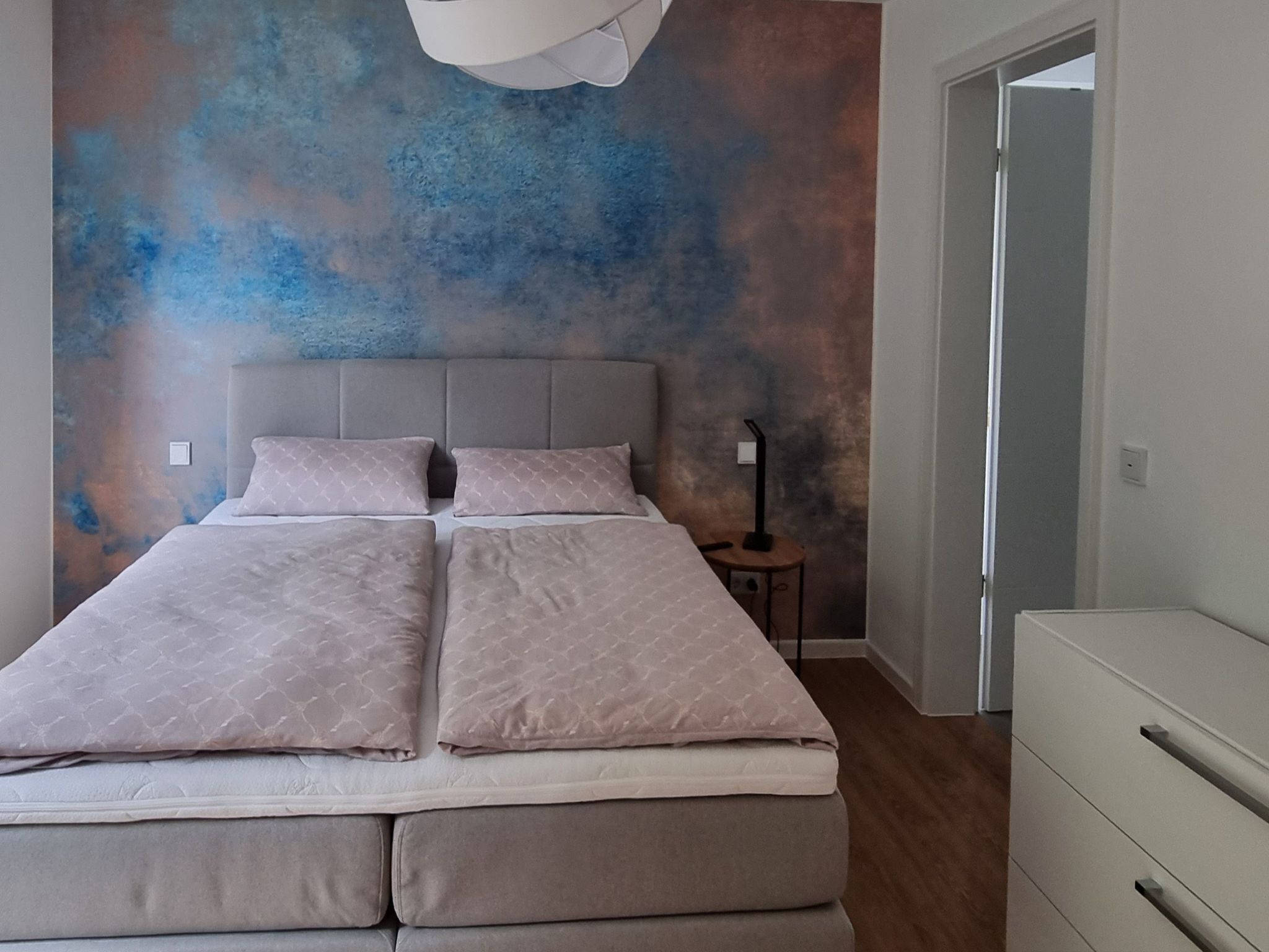 A bedroom with a bed, a bedside table, and a nightstand.