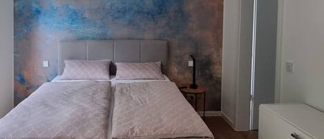 A bedroom with a bed, a bedside table, and a nightstand.