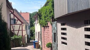 Una estrecha calle adoquinada bordeada por edificios tradicionales con vigas de madera a la vista y una estructura moderna con techo inclinado.