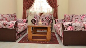 En stue med blomstermønstrede sofaer, et træbord og en dekorativ vase.
