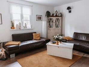 A living room with two dark brown leather sofas, a white coffee table, and a wooden cabinet with glass doors. - in Erlbach mit Grill und Terrasse by Interhome (Markneukirchen)