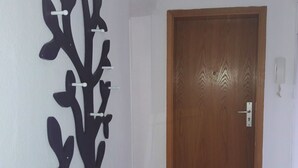 Une porte en bois avec un trou de serrure et une poignée en métal, ainsi qu’un élément décoratif fixé au mur, composé de plusieurs branches et de crochets.