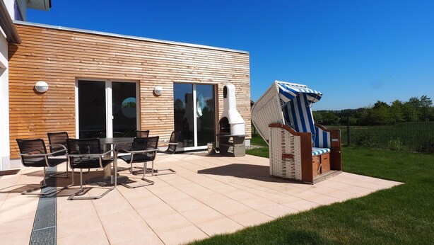 Une terrasse extérieure moderne, dotée d’une plateforme en bois, d’un barbecue et de mobilier d’extérieur.