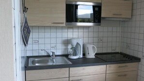 Una cocina moderna con un microondas de acero inoxidable, una cafetera y un hervidor sobre la encimera.