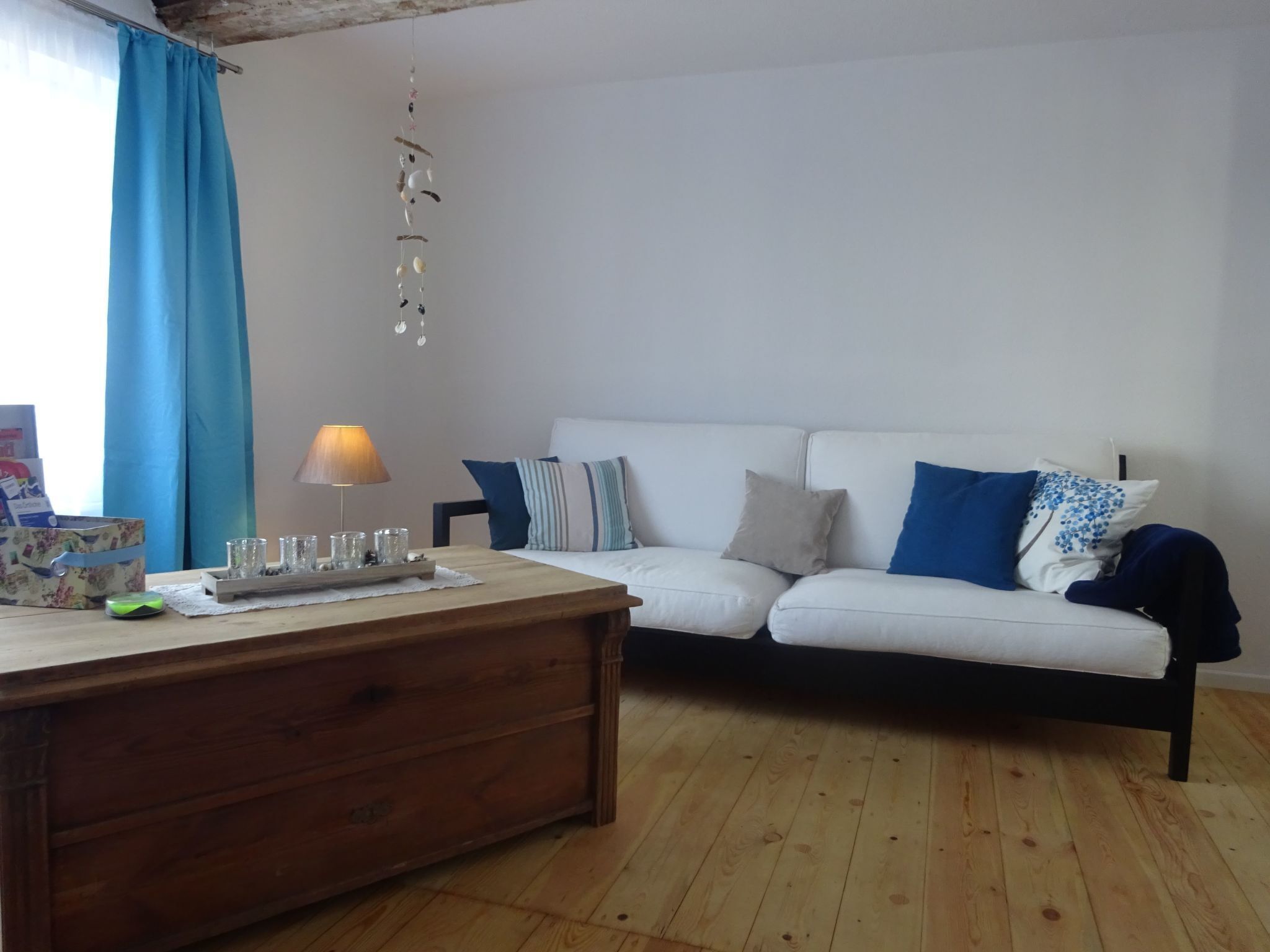 Una sala de estar con un sofá blanco, una mesa de centro de madera y una lámpara.