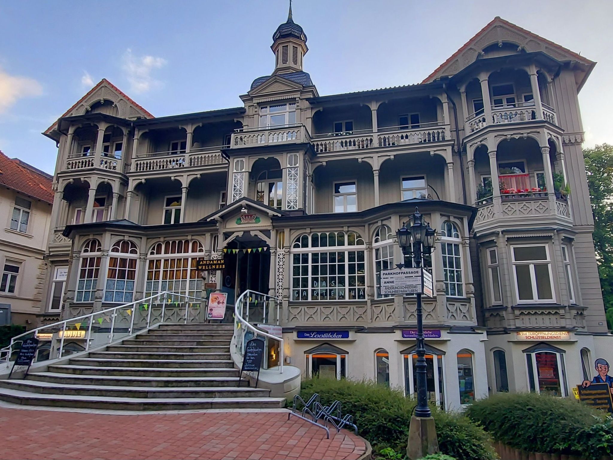 Ein historisches Gebäude mit mehreren Balkonen, einem zentralen Turm und einer Treppe, die zum Eingang führt.