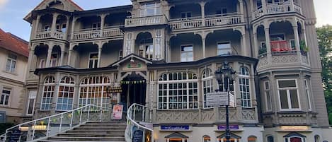 Un edificio histórico con varios balcones, una torre central y una escalera que lleva a la entrada.