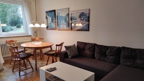 Un salon chaleureux avec une table à manger en bois, des chaises, un canapé et des œuvres d’art accrochées au mur.
