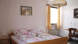 Een slaapkamer met een houten bed, een nachtkastje, een bureau en een stoel.