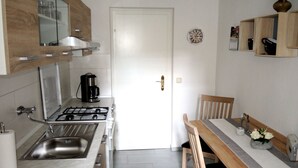 Une cuisine de taille réduite équipée d’une cuisinière à gaz, d’un évier et d’une table à manger avec des chaises.