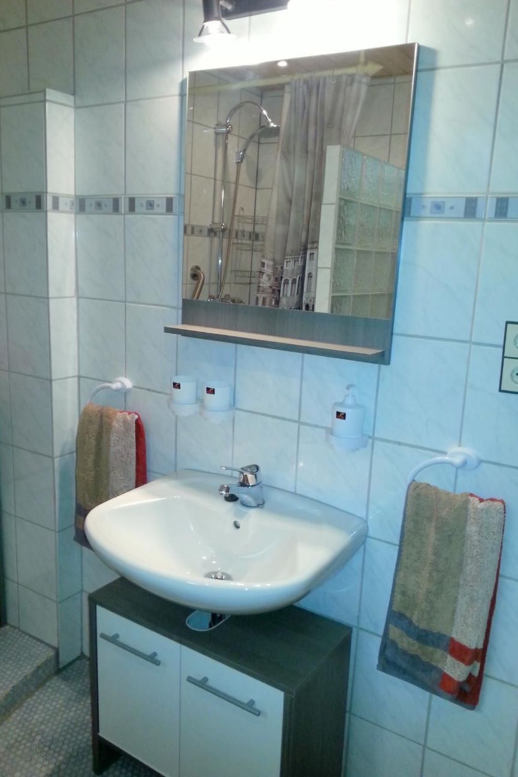 Une salle de bain avec un lavabo blanc, un miroir et un porte-serviettes.