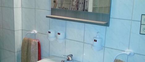 Une salle de bain avec un lavabo blanc, un miroir et un porte-serviettes.