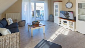 Ein gemütliches Wohnzimmer mit einer Couch, einem Couchtisch und einem Fernseher.
