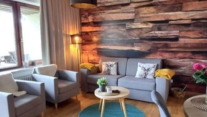 Una sala moderna con un sofá gris, una mesa de centro redonda y una pared decorativa de madera.