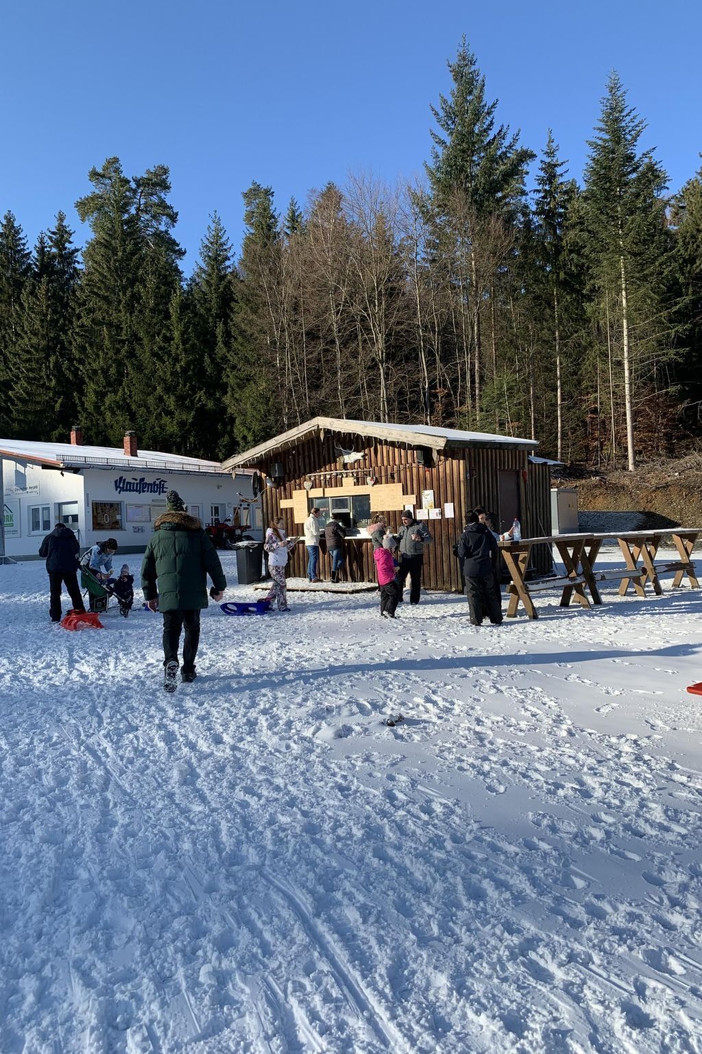 Un espace extérieur enneigé avec un bâtiment en bois, peut-être un chalet ou une cabane, entouré d’arbres.
