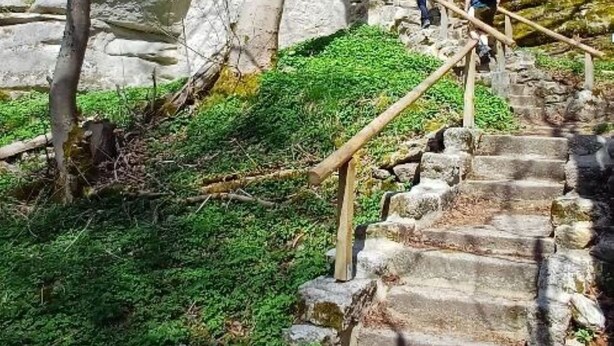 Una escalera de piedra que conduce a un edificio con un telón de fondo de formaciones rocosas naturales.