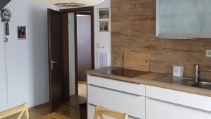 Une cuisine compacte avec un revêtement mural en bois, un luminaire suspendu moderne et un micro-ondes encastré.