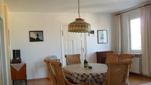 A dining area with a round table, wicker chairs, a patterned tablecloth, a hanging lamp, and a window with curtains. - in Gründerzeitvilla in Strandnähe by Interhome (Ahlbeck)