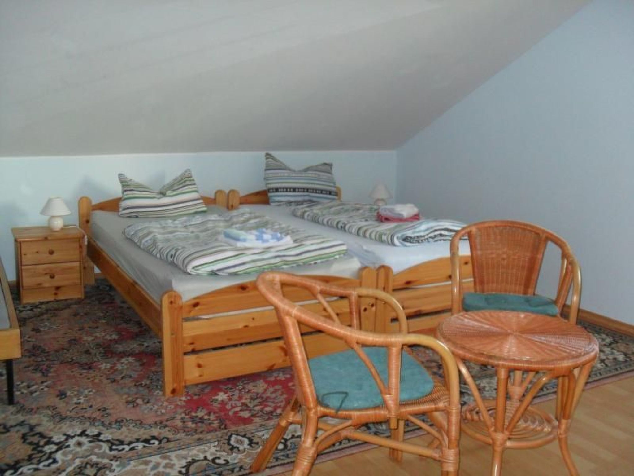 A bedroom with a single bed, two bedside tables, a chair, and a small table.