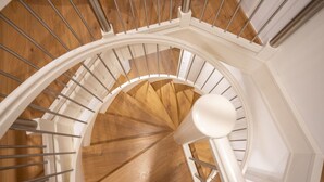 Una escalera en espiral con escalones de madera y barandillas blancas.