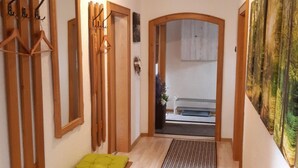 Un couloir avec des bancs en bois, un miroir et un tableau accroché au mur.